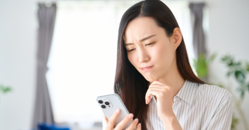 スマホを見て悩む女性